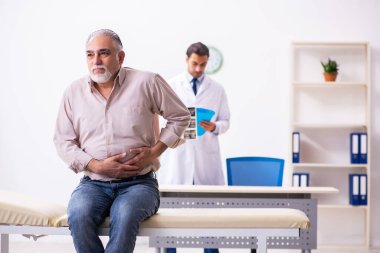 Yaşlı hasta genç erkek doktoru ziyaret ediyor.