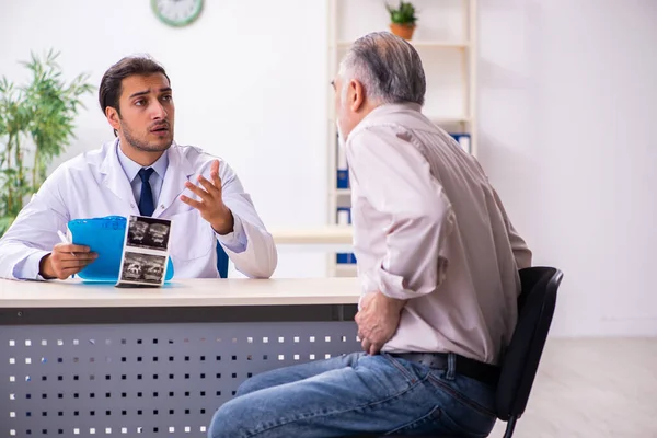 Viejo paciente visitando joven médico masculino —  Fotos de Stock