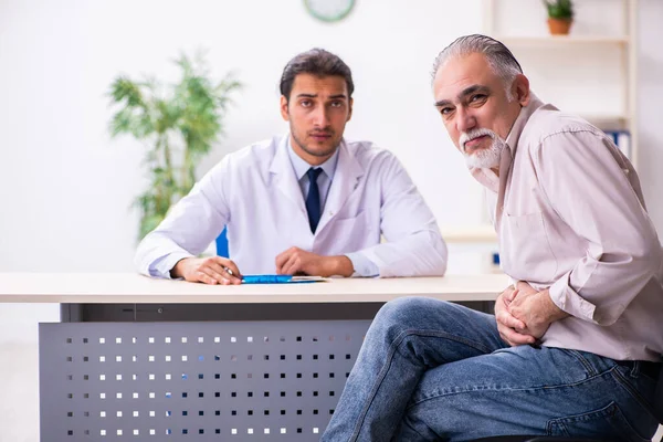 Yaşlı hasta genç erkek doktoru ziyaret ediyor. — Stok fotoğraf