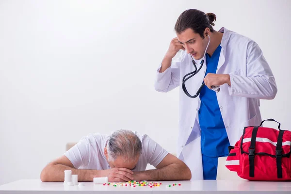 Young male doctor visiting old male patient at home — Stock Photo, Image