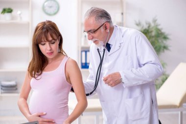 Genç hamile kadın yaşlı erkek jinekoloğu ziyaret ediyor.