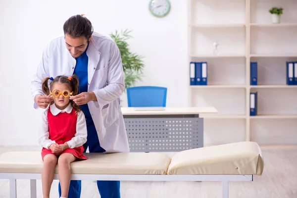 Menina pequena visitando jovem médico oculista masculino — Fotografia de Stock