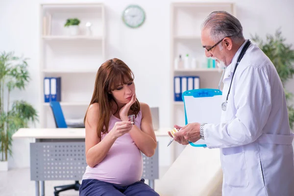 Jovem mulher grávida visitando velho médico ginecologista masculino — Fotografia de Stock