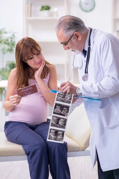 Giovane donna incinta visita vecchio medico ginecologo maschile — Foto Stock