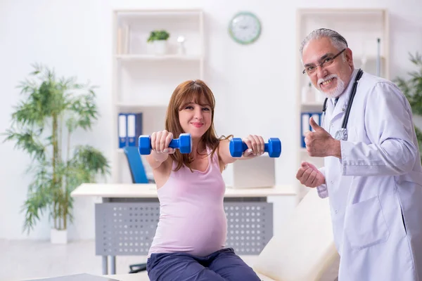 Jonge zwangere vrouw bezoekt oude mannelijke arts gynaecoloog — Stockfoto