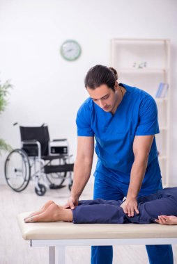 Yaralı kadın genç erkek doktor osteopat 'ı ziyaret ediyor.