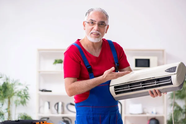 Viejo contratista reparando aire acondicionado en interiores —  Fotos de Stock