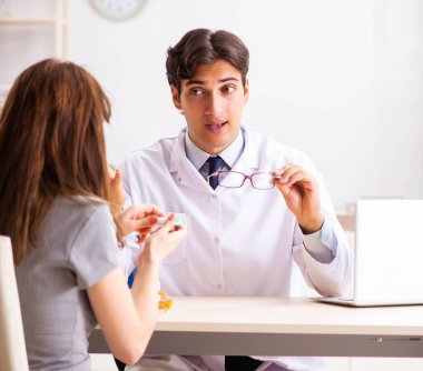 Genç bir kadın, erkek doktor göz doktorunu hastanede ziyaret ediyor.