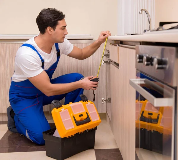 Joven reparador trabajando en la cocina — Foto de Stock