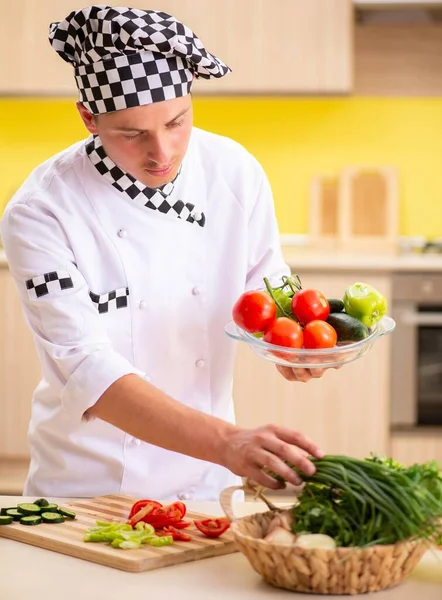 Joven cocinero profesional preparando ensalada en la cocina — Foto de Stock