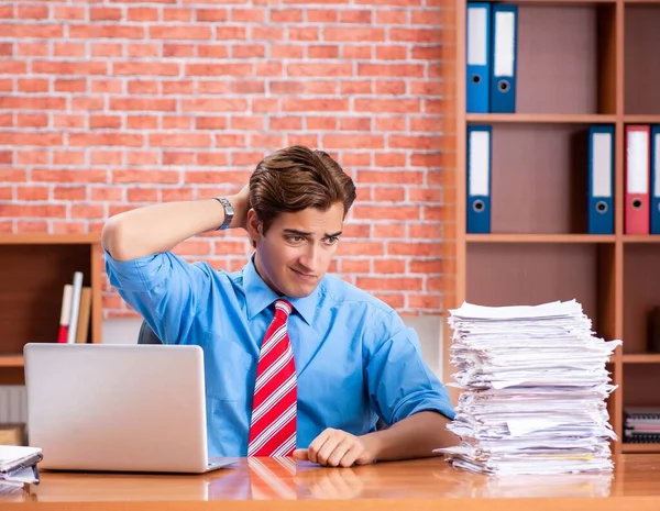 オフィスに座って過剰な仕事を持つ若い従業員 — ストック写真