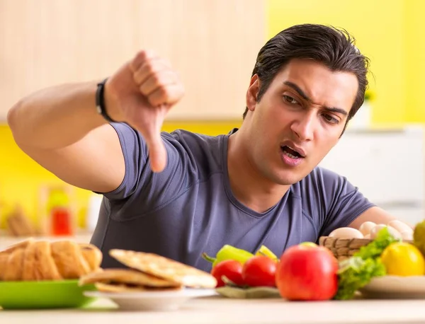 Homem tendo escolha difícil entre alimentos saudáveis e não saudáveis — Fotografia de Stock