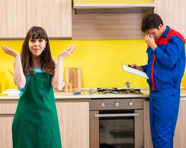 Frau diskutiert mit Bauunternehmer in Küche über Reparatur — Stockfoto