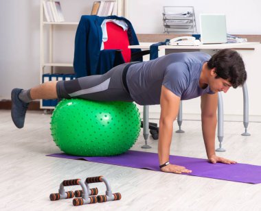 Ofiste egzersiz yapan genç bir erkek.