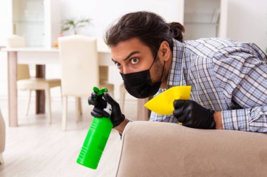 Genç erkek müteahhit Coronavirus konseptiyle evi temizliyor.