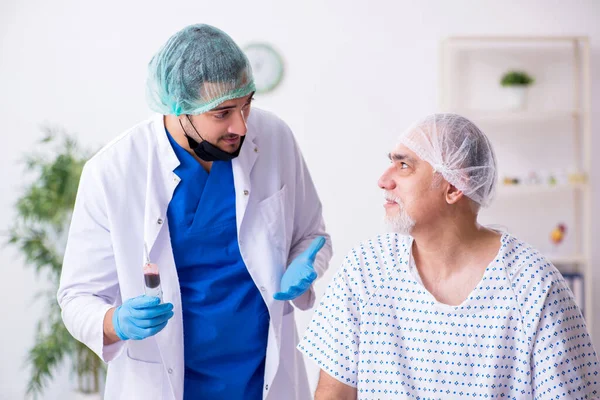 Vecchio visita giovane maschio stagista medico — Foto Stock