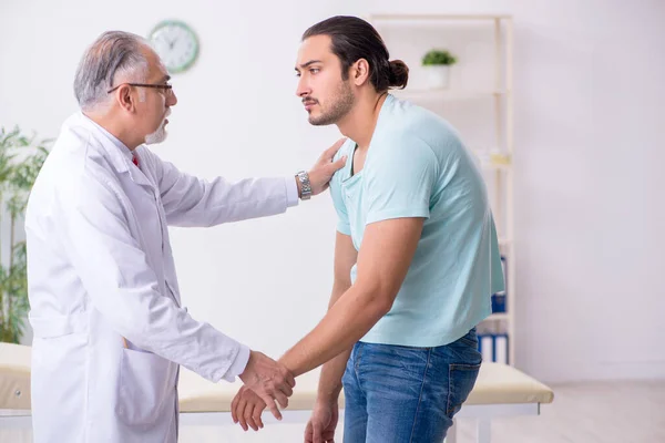 Genç sırtı yaralı adam deneyimli erkek doktoru ziyaret ediyor. — Stok fotoğraf