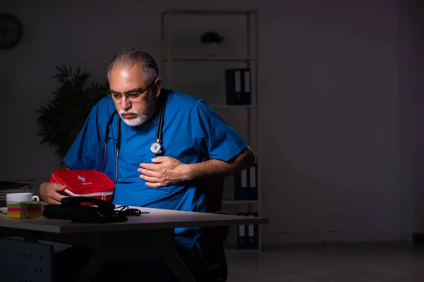 Aged male doctor in the hospital at night — Stock Photo, Image