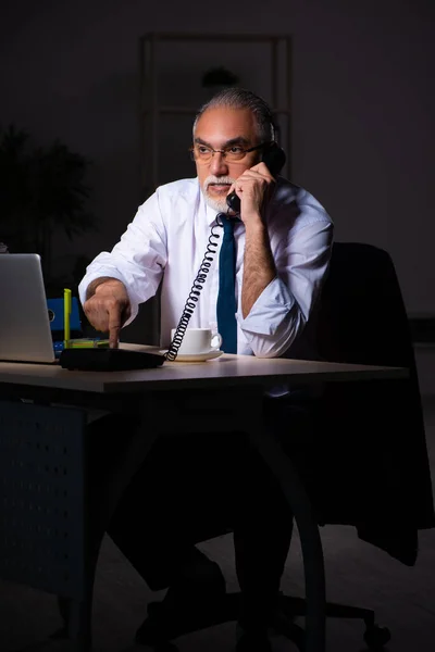 Velho empregado do sexo masculino que trabalha até tarde no local de trabalho — Fotografia de Stock