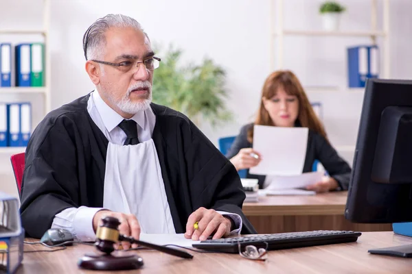 Oude mannelijke rechter en zijn jonge secretaresse op kantoor — Stockfoto