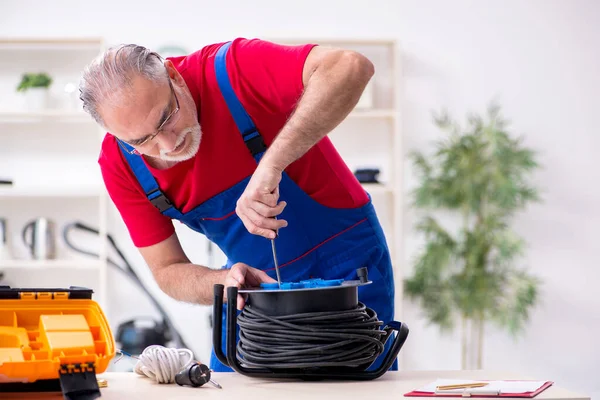 Velho empreiteiro masculino segurando bobina de cabo dentro de casa — Fotografia de Stock
