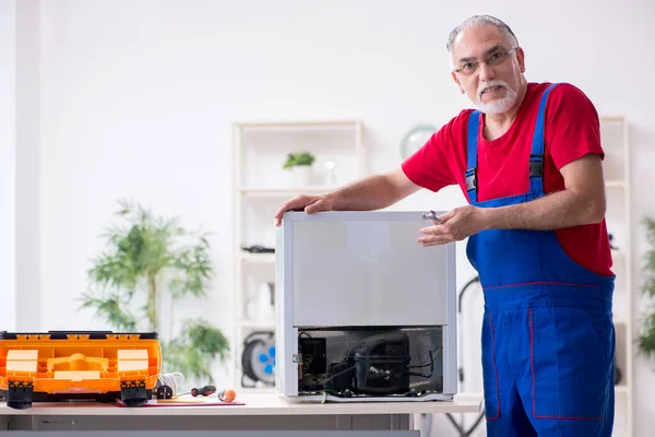 Yaşlı erkek müteahhit içeride buzdolabını tamir ediyor. — Stok fotoğraf