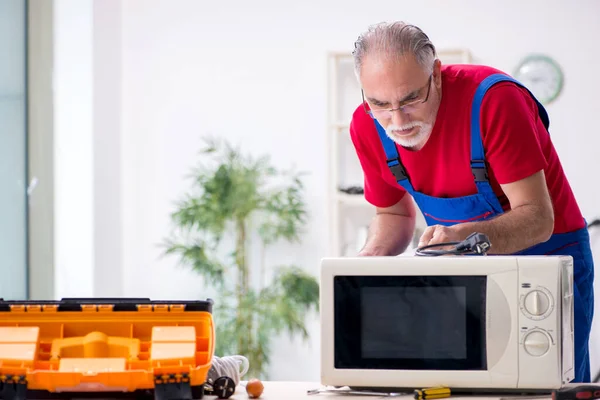 Ancien entrepreneur masculin réparer micro-ondes à l'intérieur — Photo