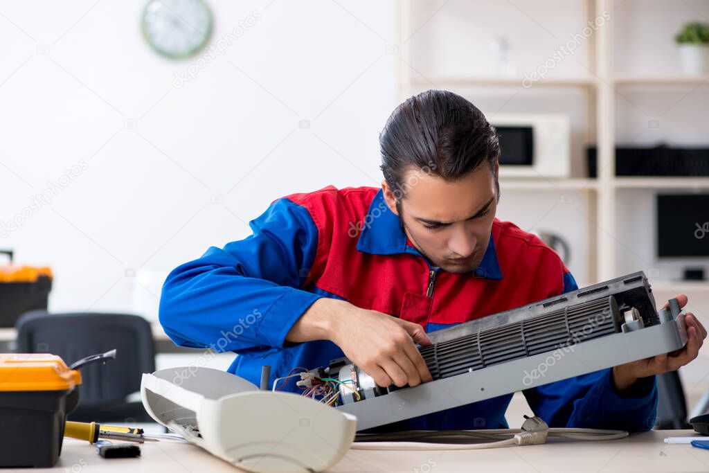 Young repairman repairing air-conditioner at warranty center
