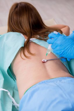 Genç sırtı yaralı kadın, erkek doktor masörünü ziyaret ediyor.