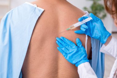 Genç sırtı yaralı bir adam, kadın doktor masörünü ziyaret ediyor.