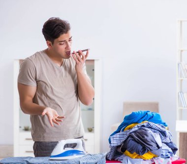 Genç adam evde çamaşır ütülüyor.