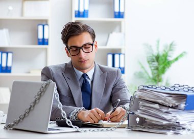 Ofis masasına zincirlenmiş meşgul bir çalışan.