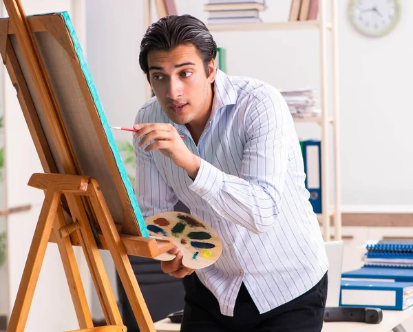 Jovem e bonito funcionário desfrutando de pintura no escritório — Fotografia de Stock