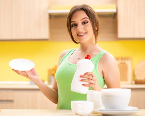 Giovane donna pulizia e lavaggio piatti in cucina — Foto Stock