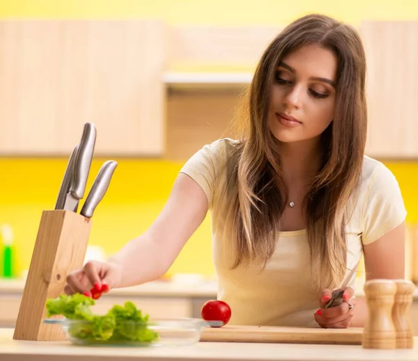 Mujer joven preparando ensalada en casa en la cocina — Foto de Stock