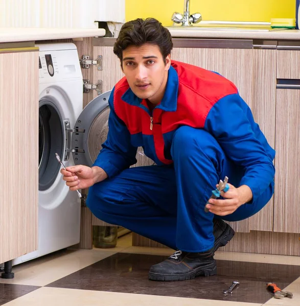 Reparador reparando lavadora en la cocina — Foto de Stock