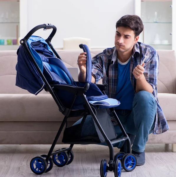 Jovem pai montando carrinho de bebê em casa — Fotografia de Stock