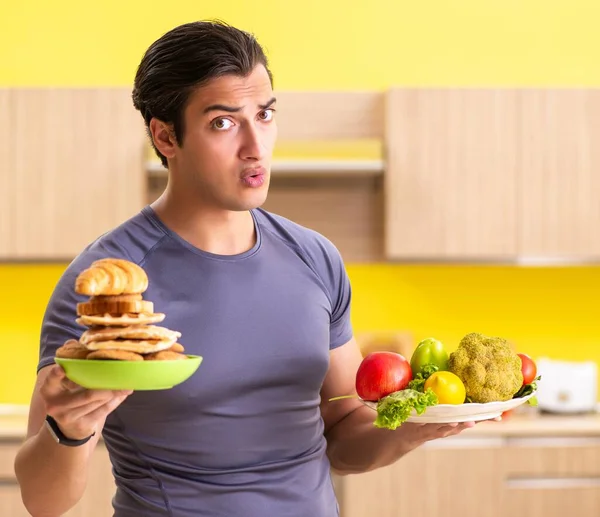 Hombre que tiene difícil elección entre la comida sana y no saludable —  Fotos de Stock