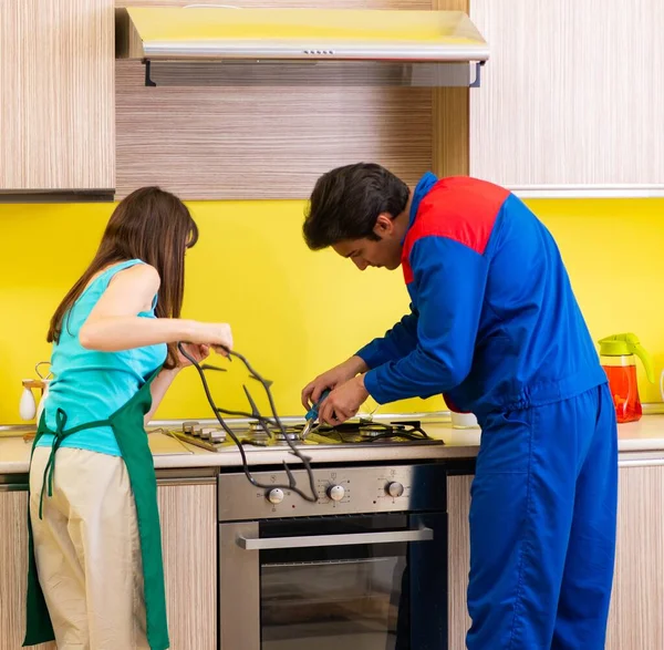 Frau diskutiert mit Bauunternehmer in Küche über Reparatur — Stockfoto