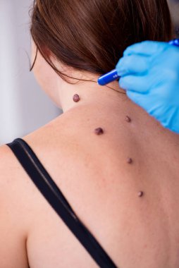 Genç bir kadın erkek doktor dermatoloğunu ziyaret ediyor.