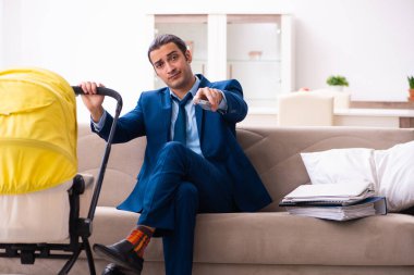 Genç işadamı evde yeni doğan bebeğe bakıyor.