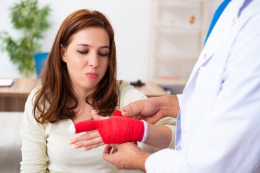 Genç el yaralı kadın erkek doktor travmatoloğu ziyaret ediyor.