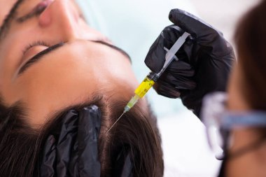 Genç adam saç nakli dolandırıcılığında kadın güzellik uzmanını ziyaret ediyor.