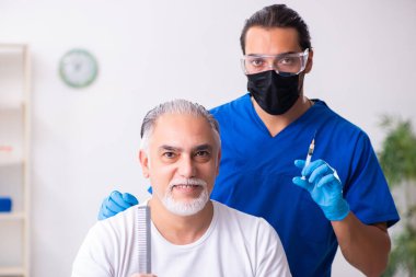 Yaşlı adam saç nakli için genç erkek doktoru ziyaret ediyor.