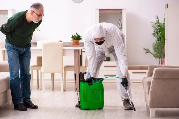 Young male sanitizer and old man indoors