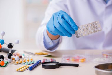Uyuşturucu sentezi konseptinde genç erkek laboratuvar asistanı