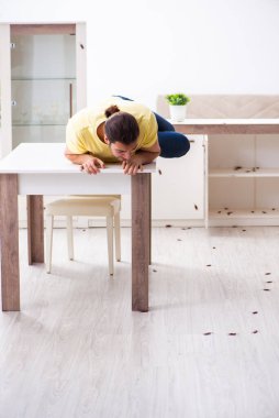 Genç adam ve evde bir sürü hamamböceği var.