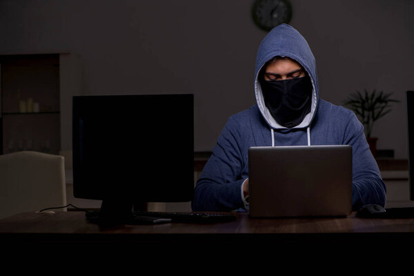 Male hacker hacking security firewall late in office