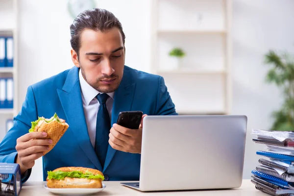 Joven empleado masculino desayunando en el lugar de trabajo — Foto de Stock