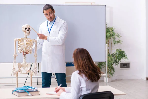 Молодой врач-педагог, скелет и студентка в CL — стоковое фото